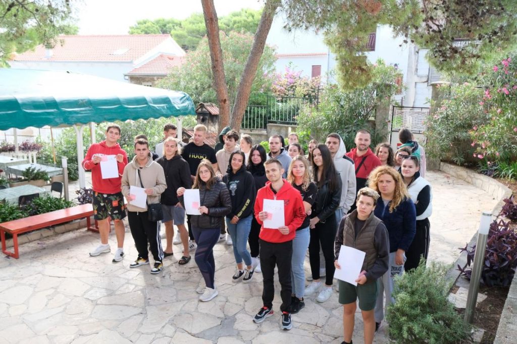Učesnici projekta Today4Tomorrow na zajedničkoj fotografiji u dvorištu; nekoliko učesnika drži listove papira.
